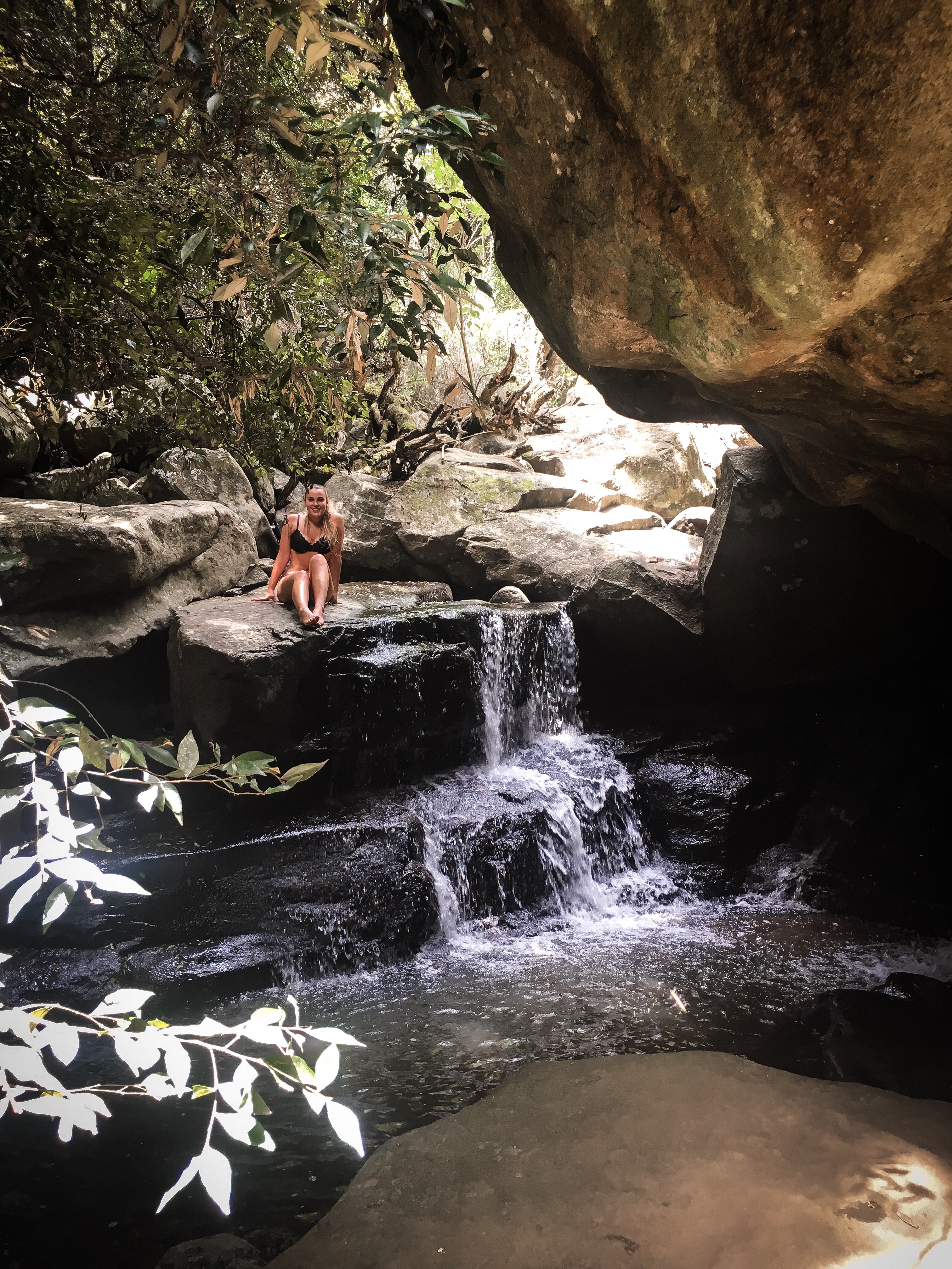 Mädchen auf einem Stein im Dschungel neben einem Wasserfall